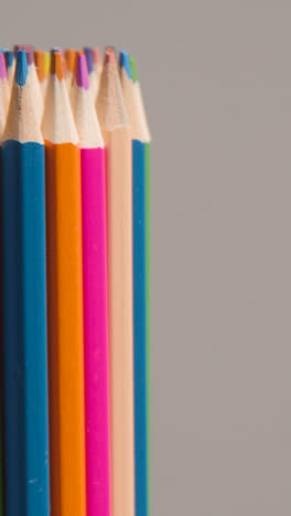 Vertical-Video-Studio-Shot-Of-Rotating-Multi-Coloured-Pencils-Against-Grey-Background-